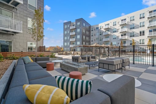 an outdoor lounge area with couches and tables with buildings in the background