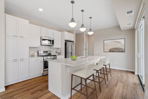 a white kitchen with a large island with chairs