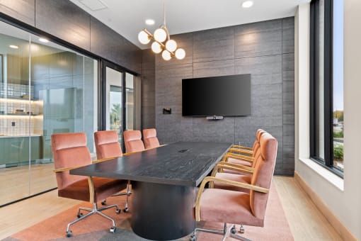 a conference room with a long table and chairs and a television