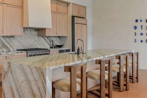 A kitchen with a marble countertop and wooden bar stools.