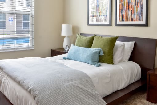 a bedroom with a large bed with green and white pillows