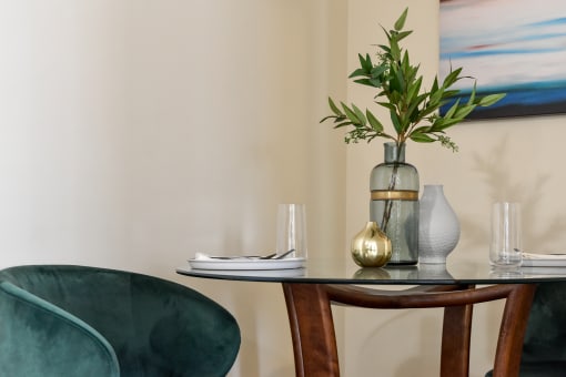 a table with green chairs and a vase with flowers on it
