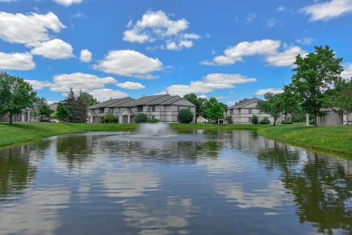 a pond in front of a house with a fountain
