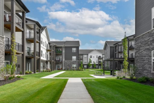 an exterior view of an apartment complex with a green lawn at The Commons at Rivertown, Grandville, MI, 49418