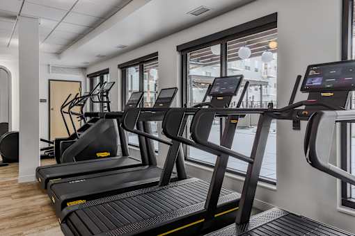 A gym with treadmills and a view of the street outside.