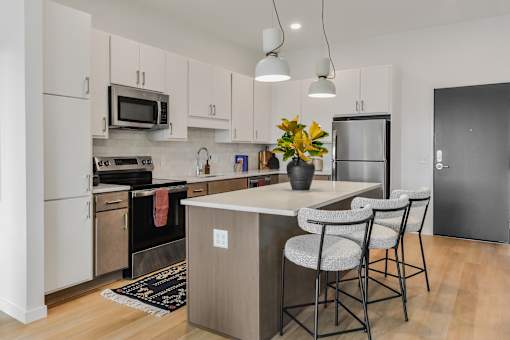 A kitchen with a white counter top and grey chairs.