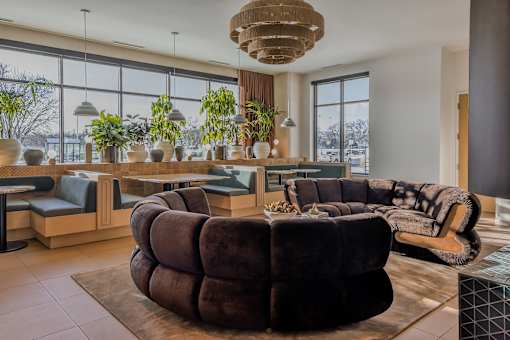 A large brown circular sofa is in the center of a well-decorated room.