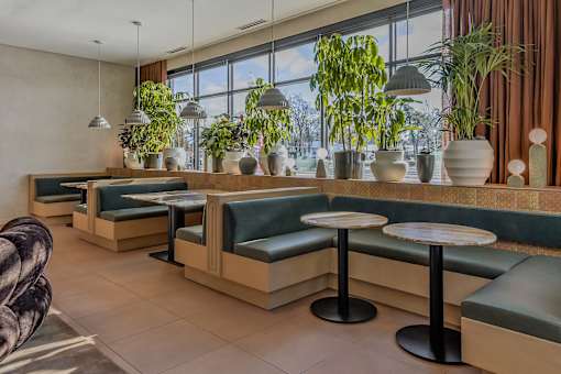 A restaurant with green plants and wooden tables.