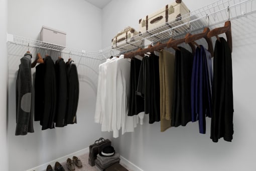 a closet filled with clothes hanging on a rack and shoes on the floor at The Aurilla, Cottage Grove, MN