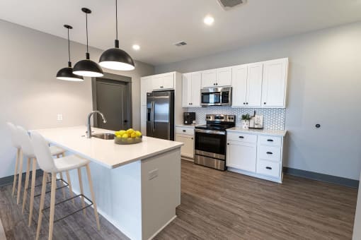 a kitchen with white cabinets and a large island with a white counter top at The Commons at Rivertown, MI