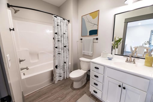 a bathroom with a shower toilet and sink and a mirror at The Commons at Rivertown, MI