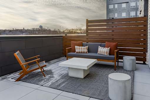 A wooden chair and a white table are on a patio.