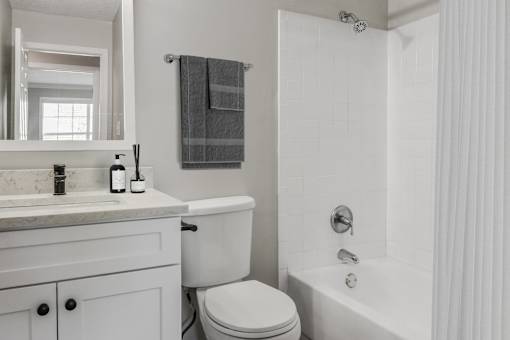A white bathroom with a toilet, sink, and bathtub.