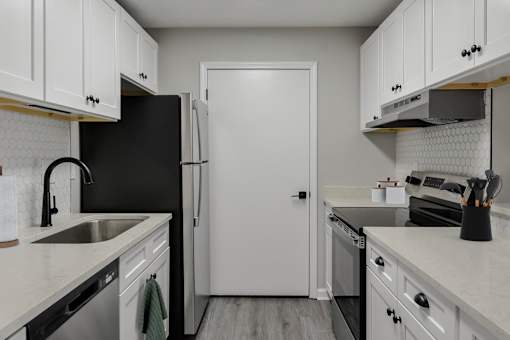 A kitchen with black and white appliances and cabinets.