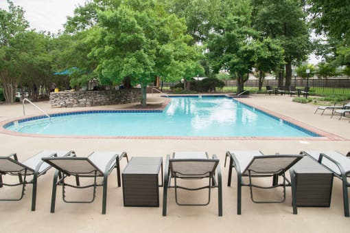 a swimming pool with lounge chairs and trees in the background  at Riverset Apartments, Memphis