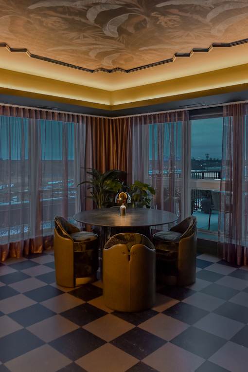A round table with four chairs is in the middle of a room with a checkered floor.