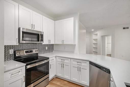 A kitchen with white cabinets and appliances.