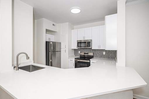 A kitchen with white countertops and stainless steel appliances.