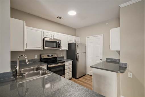 A kitchen with a stove, oven, refrigerator, and microwave.