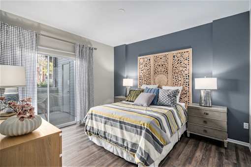 A bedroom with a bed, nightstand, and a large decorative wall panel.