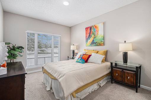 A bedroom with a bed, nightstands, and a painting on the wall.