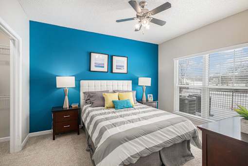 A bedroom with a bed, two lamps, and two pictures on the wall.