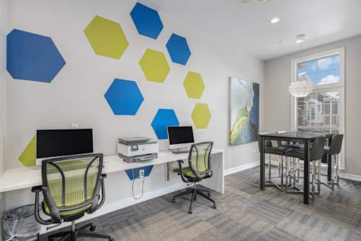 A room with a desk, chairs and a wall with hexagonal shapes on it.