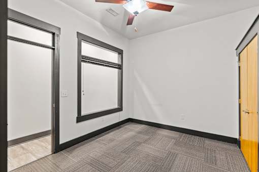 A room with a ceiling fan and carpeted floor.