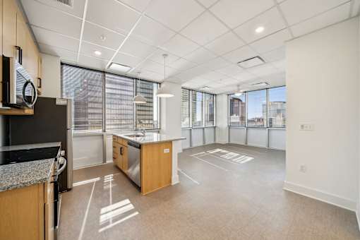 A spacious kitchen and living room area with a large window and a view of the city.
