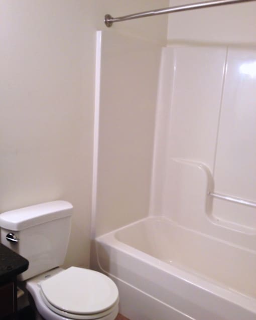 A white toilet sits next to a white bathtub in a bathroom.