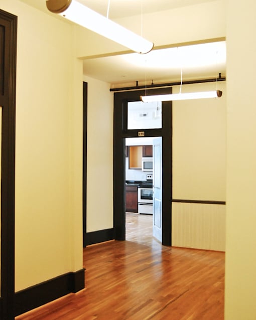 A hallway with a kitchen visible through the door.