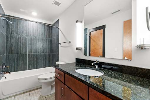 A bathroom with a black granite countertop and a white bathtub.