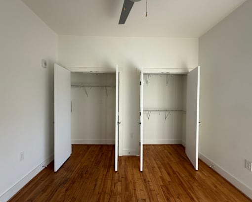 A room with two closets and a ceiling fan.