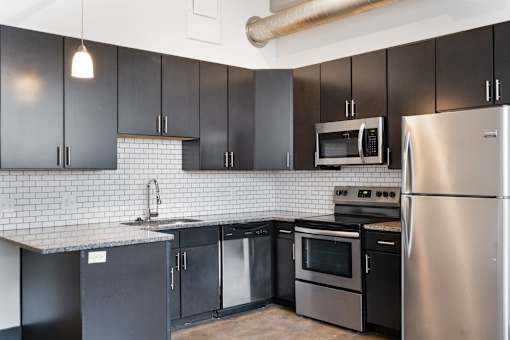 A kitchen with black cabinets and stainless steel appliances.
