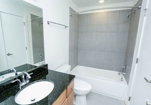 A bathroom with a black granite countertop and white fixtures.