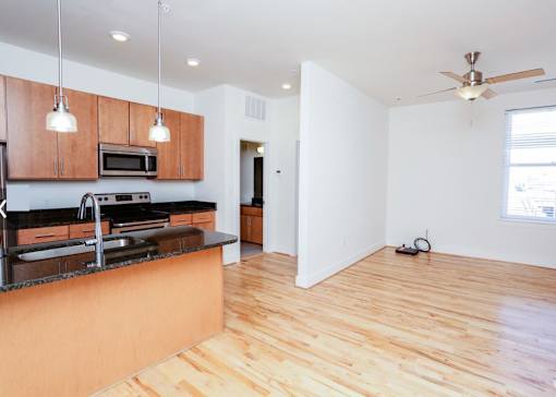 A kitchen with wooden floors and a black counter top.