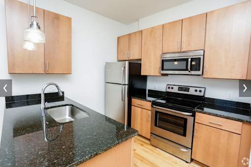 A kitchen with wooden cabinets and black countertops.