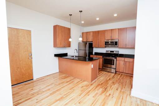 A kitchen with wooden floors and a black counter.