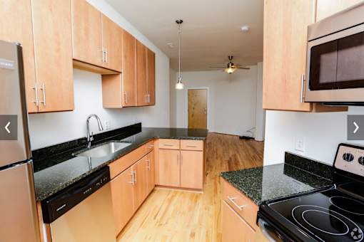 A kitchen with wooden cabinets and black countertops.
