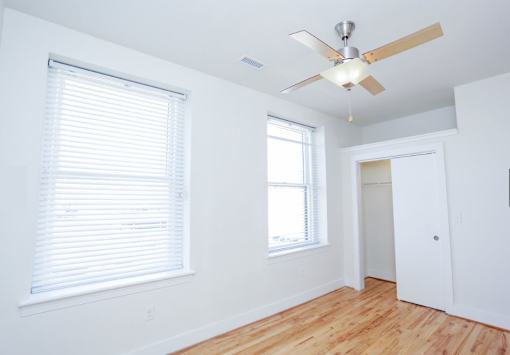 A room with a ceiling fan and a window with blinds.