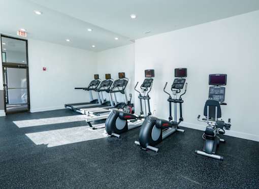 A gym with a row of exercise bikes and a door marked exit.