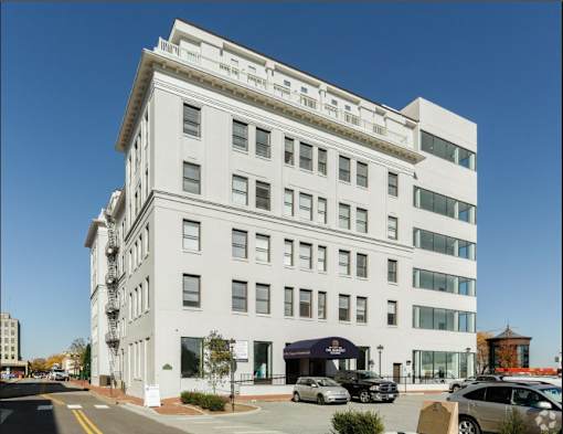 A white building with a black car parked in front.