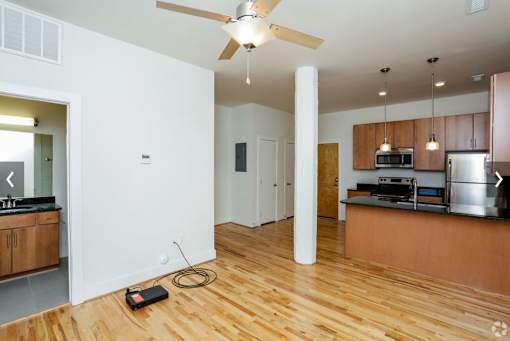 A kitchen with wooden floors and a ceiling fan.