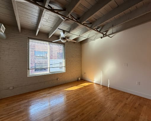 A room with wooden floors and a window with blinds.