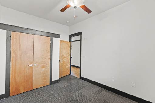 A room with a ceiling fan and a row of wooden doors.
