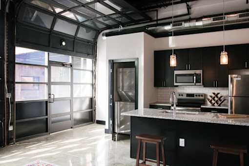A modern kitchen with a black countertop and stainless steel appliances.