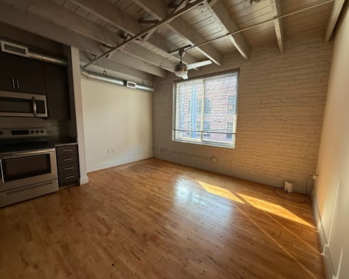 A room with wooden floors and a window letting in sunlight.