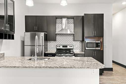 A modern kitchen with a granite countertop and stainless steel appliances.
