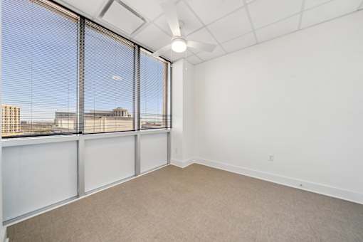 A room with a large window and a ceiling fan.
