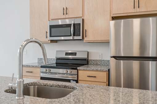 A kitchen with a stainless steel refrigerator, microwave, and oven.